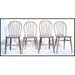 A set of four early 20th century beech and elm hoop back dining chairs in the manner of Ercol,
