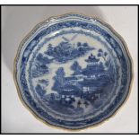 An 18th century Chinese blue and white ceramic saucer plate having a scalloped edge with hand