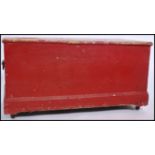 A large early 20th century pine blanket box having brass drop handles with a red painted finish. The