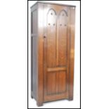 A mid century ecclesiastical hall cupboard having full length door with linen fold design opening to