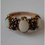 A hallmarked 9ct gold opal and sapphire ring set with three graduated oval cut opal flanked by