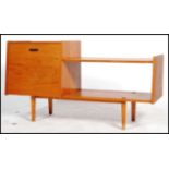 A vintage 1960's teak low sideboard media unit having a large angled drop down door adjacent to a