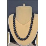 A vintage freshwater black pearl necklace strand. The pearls of varying form but similar size.