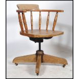 An Edwardian Industrial office swivel desk chair having spindle gallery, saddle seat with shaped