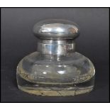 An early 20th century silver hallmarked topped cut glass desk top inkwell having a faceted glass