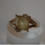 A hallmarked 9ct gold ring  set with a central cushion cut pale yellow stone having stylised diamond