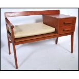 A retro mid century teak wood Danish inspired telephone table with padded seat and being raised on