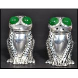 A pair of continental silver novelty pepper and salt pots in the form of frogs with green stone