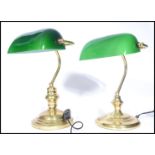 A near pair of vintage style 20th century brass bankers lamps raised on circular bases with arched