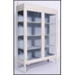 A 1920's shabby chic painted display cabinet having mesh doors with shelved interior being raised on