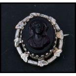 A 19th century Victorian carved glass cameo brooch in an amethyst purple colour with silver white