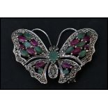 A sterling silver marcasite brooch in the form of a butterfly having ruby and emerald adorned wings.