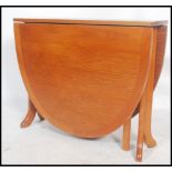 A retro 20th century G-Plan teak drop leaf dining table having shaped supports, the end leaves