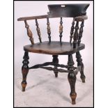 A Victorian beech and elm smokers bow Windsor Elbow chair being raised on turned legs united by