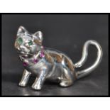 A sterling silver figurine of a cat having an inset ruby collar with emerald eyes. Weighs 12 grams.