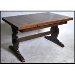 A 1930's oak Jacobean revival oak draw leaf refectory dining table being raised on lyre shaped