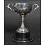 An early 20th century Art Deco silver hallmarked trophy cup raised on an ebonised wooden plinth