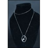 A 9ct white gold diamond pendant necklace having a circular wave pendant with diamond to centre. Set