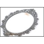 An early 20th century oval wall mirror having a silver plated scrolled and acanthus leaf frame. 34cm