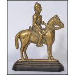 A 19th century Boer War brass doorstop in the form of a cavalry man on horse raised on a terraced