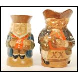 Two Doulton Lambeth Toby jugs. One seated on an X X barrel and the other riased on a domed base.