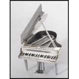 A sterling silver miniature grand piano raised on