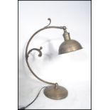 A 20th century art deco style brushed metal desk lamp having a curved arm with scroll work