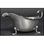 An early 20th century silver hallmarked Edwardian sauce boat having a shaped scroll handle raised on