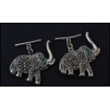 A pair of sterling silver and marcasite cuff links in the form of elephants having emerald set eyes.