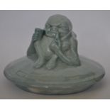 A Royal Doulton Noke blue colourway pot lid having a grotesque figure of a smoking gnome to top.