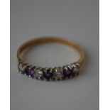 A hallmarked 9ct  seven stone gold ring being set with alternating white and purple stones.