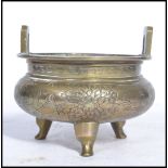 An early 20th century Chinese brass censer ding prayer bowl raised on tripod legs decorated for