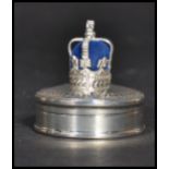 A sterling silver pill box of circular form having a blue baize pin cushion atop in the form of a