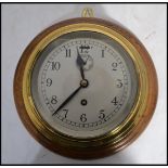 A 20th century vintage industrial brass cased ships barrel clock backed onto a circular wooden mount