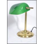 A vintage 20th century brass bankers lamp raised on a gilt circular base with adjustable green glass