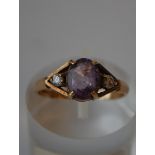 A hallmarked 9ct gold three stone ring set with a central oval cut purple stone flanked by two white