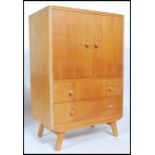 A retro 20th century limed oak tall boy, two cupboard doors opening to reveal shelved interior above