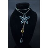 A white gold flower pendant necklace set with aquamarine and citrine stones. On silver chain