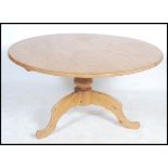 A 20th century country large pine dining table of circular form raised on a single pedestal base