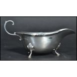 A silver hallmarked early 20th century sauce gravy boat having a shaped scroll handle raised on