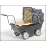 A vintage 20th century childs enamel painted pram in black with the original spoked wheels. The