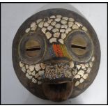 An unusual carved wooden and brass with shell inlaid wall mask. Inset with brass triangles and