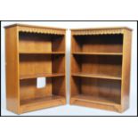 A pair of 20th century matching oak open bookcases each with a series of adjustable shelves raised