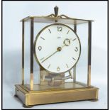 A mid century gilded brass and glass cased Kundo electronic anniversary clock with white dial and