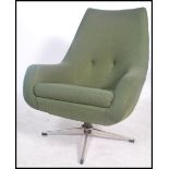 A vintage mid century retro swivel armchair raised on a polished steel five pointed base having an