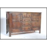 A mid 20th century Ercol beech and elm sideboard having an central bank of five / 5 drawers