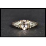 A hallmarked 9 carat gold ring with an oval clear stone in the centre with diamond chip illusion set