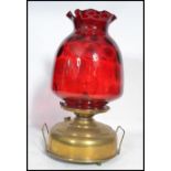 A vintage 19th century brass and cranberry glass oil lamp by Superba. The large flat brass reservoir