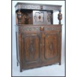 An Elizabeth style oak court cupboard, with a carved frieze top over a single door cupboard and