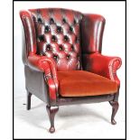 An antique style oxblood button back leather chesterfield armchair having barrel arms, raised on
